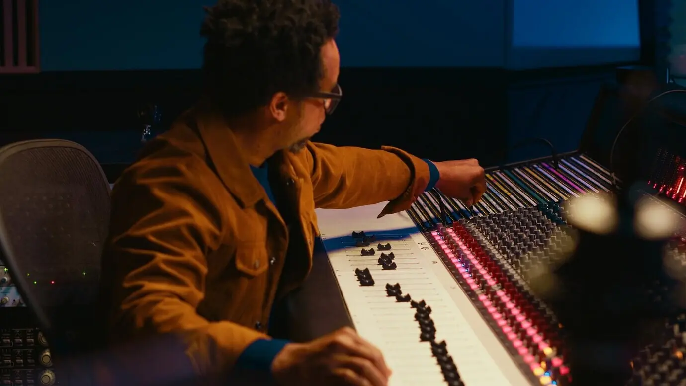 Afroamerikanischer Tonproduzent schließt ein Spiralkabel an ein Mischpult an.